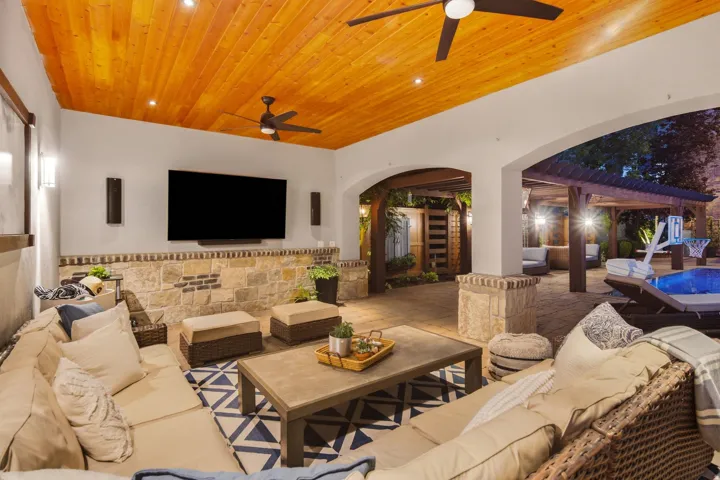 Covered outdoor patio featuring a wood-finish plank ceiling with recessed lighting and ceiling fans