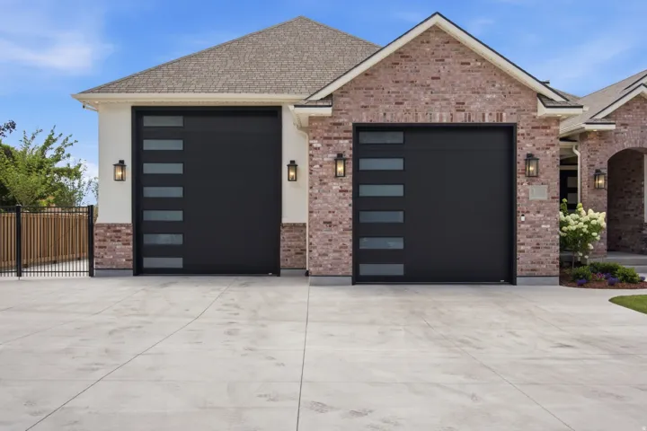 Guest House Two contemporary black garage doors with horizontal window inserts, flanked by matching exterior sconces