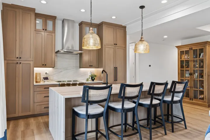 Guest House Kitchen featuring a waterfall island, recessed lighting, and two decorative pendant fixtures