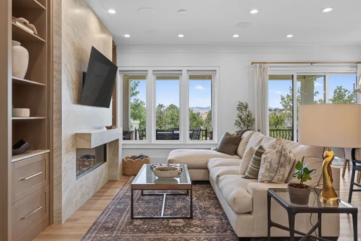 Guest House Living area featuring a floor-to-ceiling stone-look fireplace surround, built-in shelving, wood-finish flooring, recessed lighting, and expansive windows