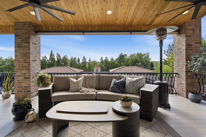 Expansive covered outdoor living area featuring a wood-panel ceiling with recessed lighting and ceiling fans