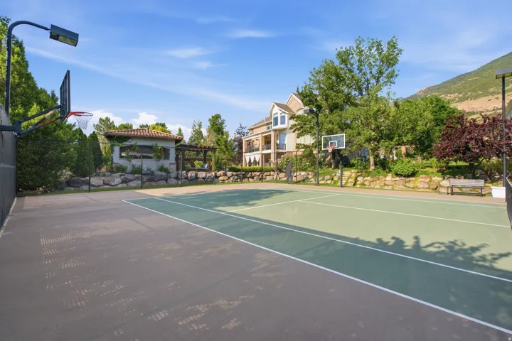 Multi-sport court featuring a tennis net and two basketball hoops with integrated lighting