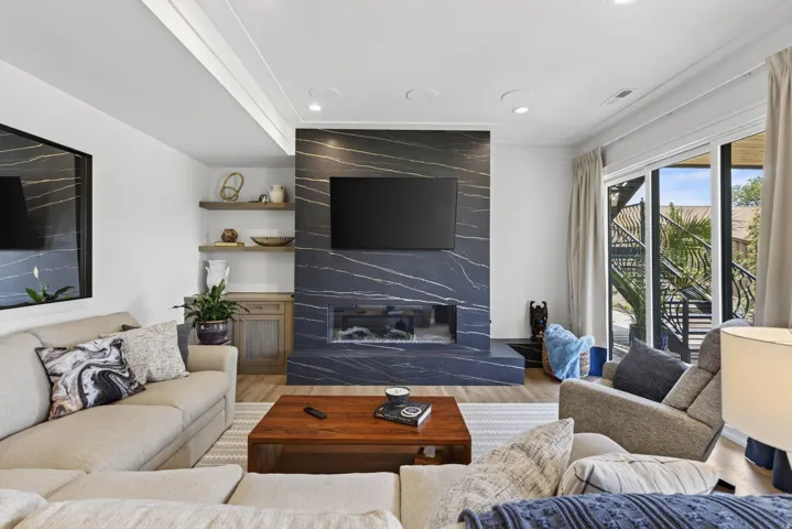 Guest House Living area featuring a floor-to-ceiling fireplace with dark, veined stone surround and an integrated linear firebox
