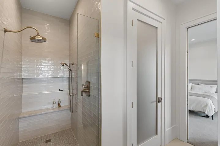 Guest House Shower enclosure featuring a rain shower head, handheld shower fixture, built-in bench, and glass paneling