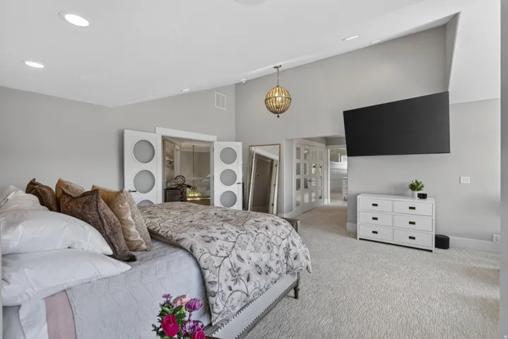 Vaulted ceiling with recessed lighting and a central chandelier