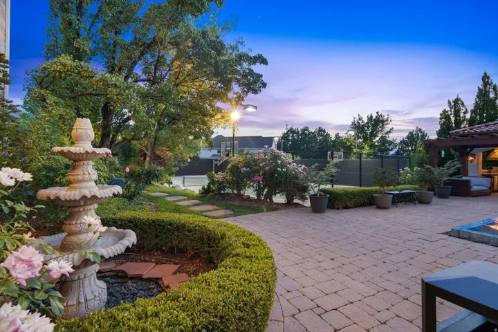Expansive paver patio featuring a built-in fire pit and a pergola-covered outdoor kitchen area