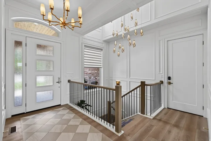 Guest House Entry foyer featuring a modern front door with sidelight and transom, geometric tile flooring, wood-finish flooring, wainscoting, and a contemporary chandelier