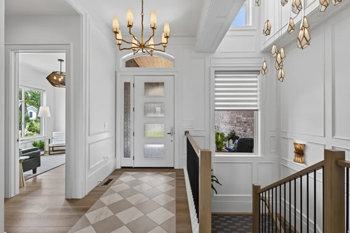 Guest House Bright entryway featuring a decorative light fixture, white paneled walls, and a multi-paneled door with frosted glass inserts
