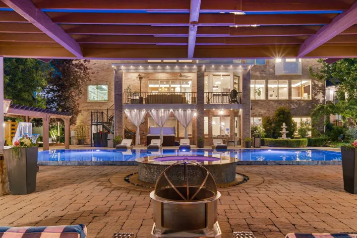 Expansive outdoor living area featuring a large swimming pool, integrated spa, and paved patio
