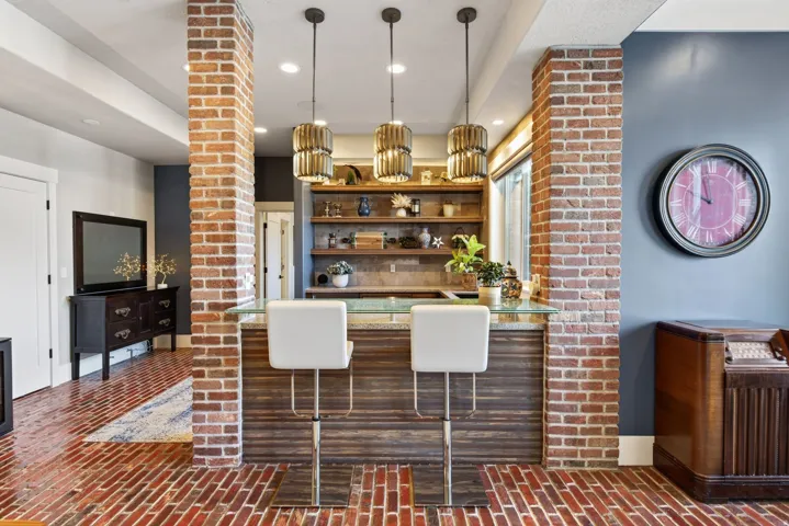 Brick flooring throughout a space featuring a built-in bar with a wood-finish base and a light-colored countertop