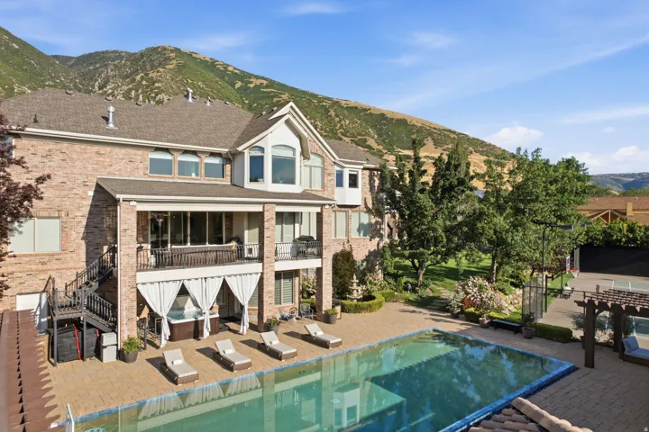 Brick exterior residence featuring a multi-level deck, a large in-ground swimming pool, and an expansive paved patio