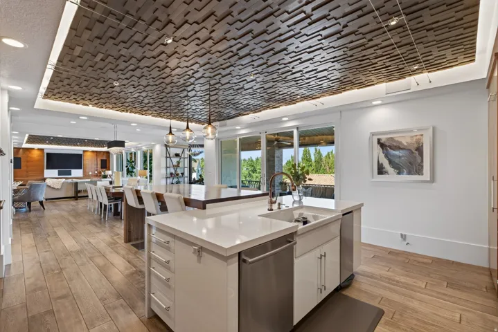 Open-concept kitchen and living area featuring a decorative wood-panel ceiling with integrated lighting