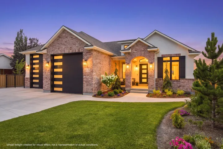 Guest House Brick and stucco exterior featuring a covered entry, decorative garage doors, and landscaped grounds