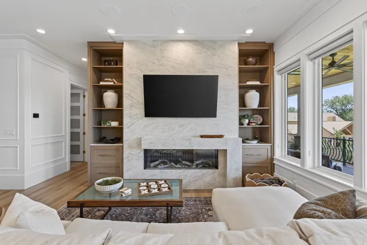 Guest House Integrated entertainment wall featuring a contemporary fireplace with a stone surround, built-in shelving, and lower cabinetry