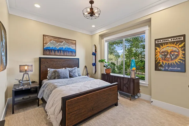 Bedroom featuring a large window, a wood-finish bed frame, and carpeted flooring