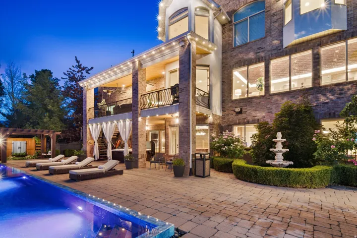 Spacious paver patio with an in-ground pool, covered patio, balcony, and tiered fountain
