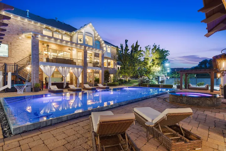 Expansive paver patio featuring a large swimming pool, integrated spa, and outdoor pergola