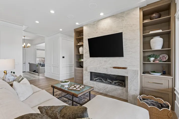 Guest House Living area featuring a gas fireplace with a stone surround, built-in shelving, recessed lighting, and wood-finish flooring