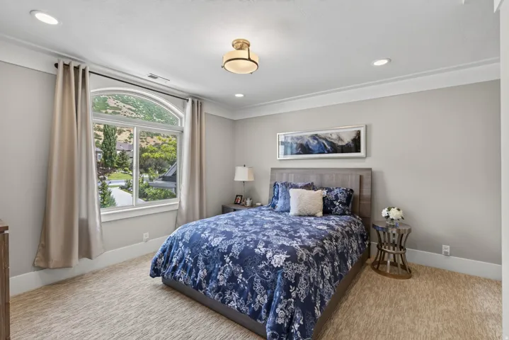 Bedroom featuring an arched window, recessed lighting, crown molding, and neutral-toned wall paint