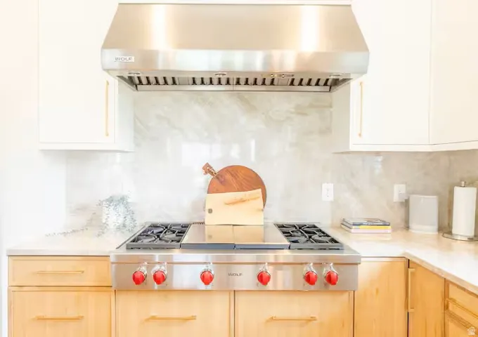 Stainless steel range with red accent knobs, complemented by a stainless steel range hood