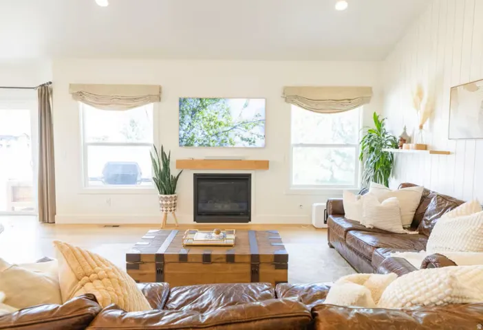 Open-concept living area featuring a fireplace with a wood mantel, light wood-finish flooring, recessed lighting, and vertical shiplap accent wall