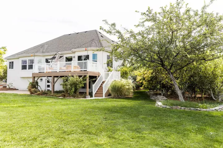 Rear elevation featuring a spacious wood-finish deck with white railings and a multi-level staircase