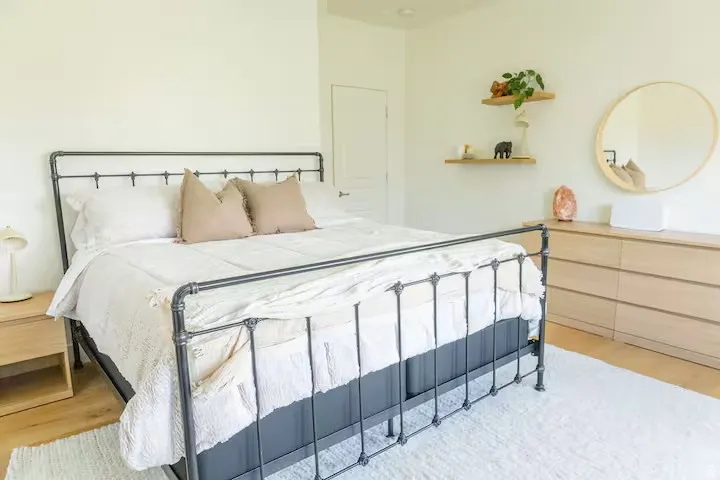 Bedroom featuring light-toned walls, wood-finish flooring, a white area rug, and a solid door