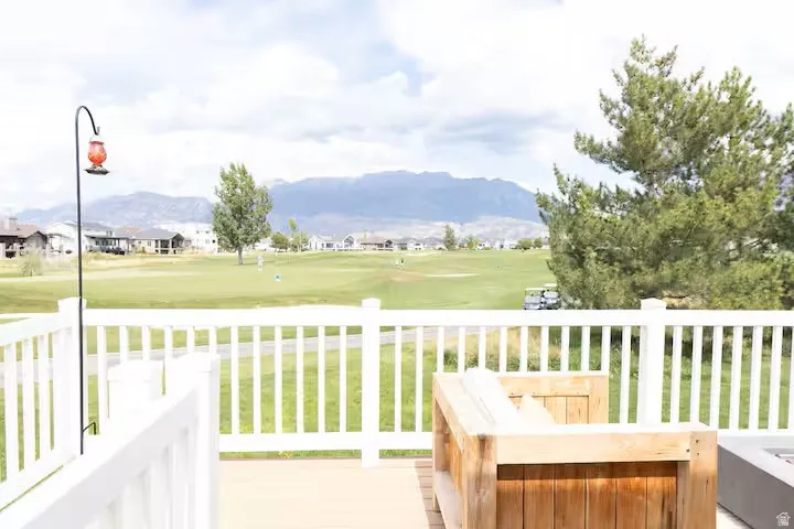 Expansive outdoor deck featuring a white railing system, wood-finish flooring, and a broad golf course panorama