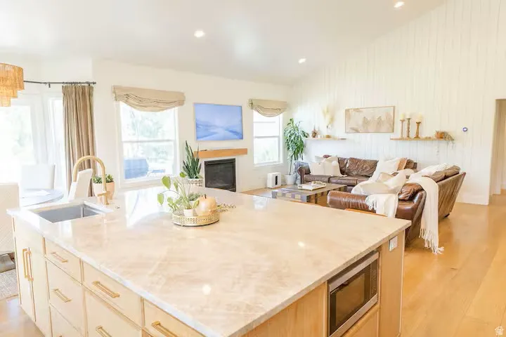 Spacious kitchen island with integrated sink and microwave, light wood-finish cabinetry, and gold-tone hardware