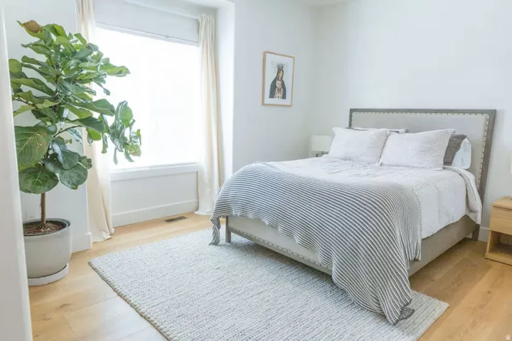 Bright interior space featuring a large window with white trim, light wood-finish flooring, and a neutral color palette