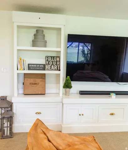 Built-in white cabinetry featuring open shelving and closed storage with brass hardware