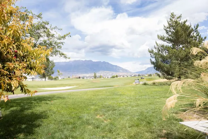 Expansive green space featuring a golf course, mountain backdrop, and scattered residential properties