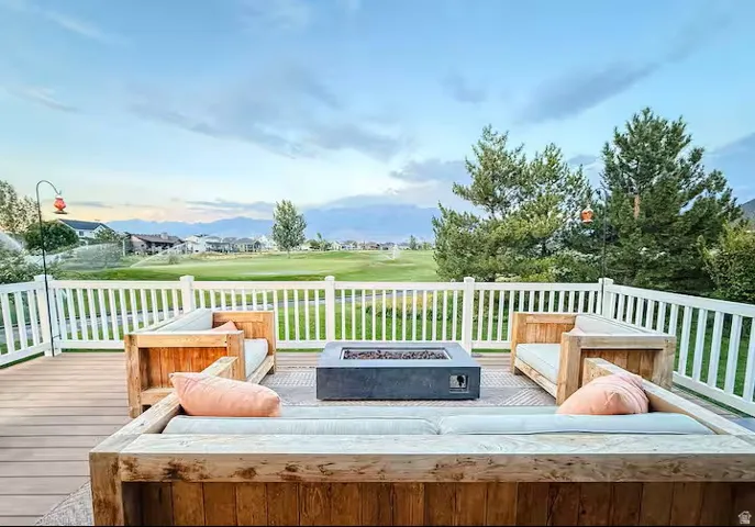 Spacious outdoor deck featuring wood-finish flooring, white railing, and a central fire pit