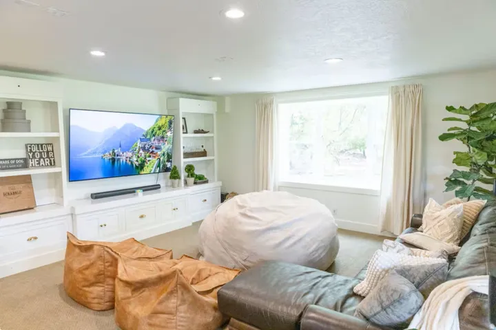 Living area featuring a large window with drapes, recessed lighting, and built-in cabinetry with shelving and drawers