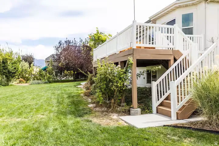 Spacious rear yard with a tiered wood deck featuring white railings and stairs