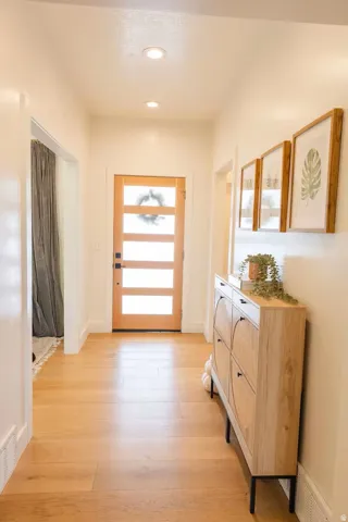Entryway featuring wood-finish flooring, recessed lighting, and a contemporary wooden front door with frosted glass panels
