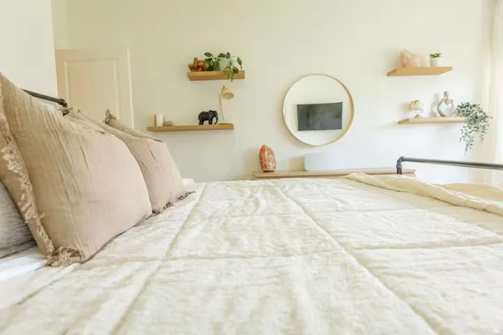 Bright bedroom featuring light-colored walls and a textured textile headboard