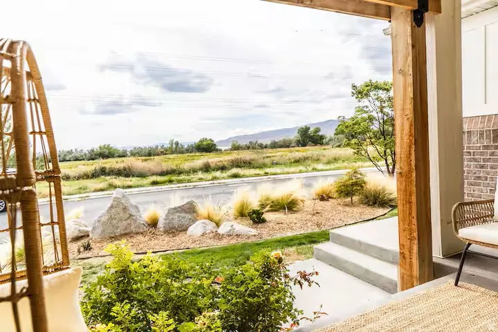 Covered patio featuring a wood support beam, exposed brick accent, and a concrete steps
