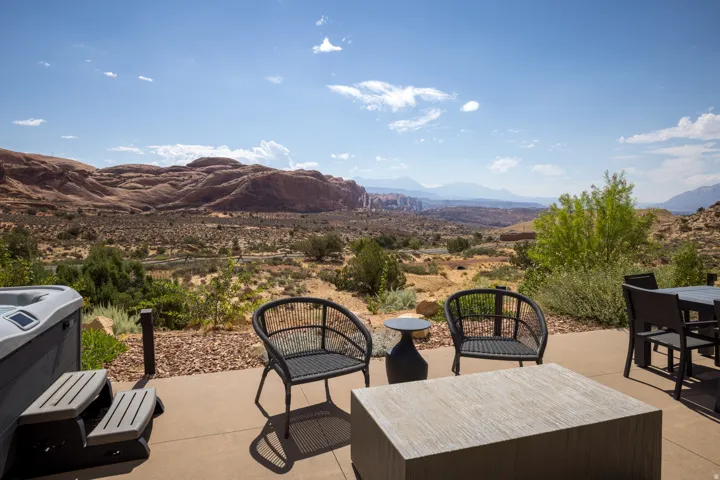 Spacious outdoor patio with a hot tub, concrete paving, and a distant mountain backdrop