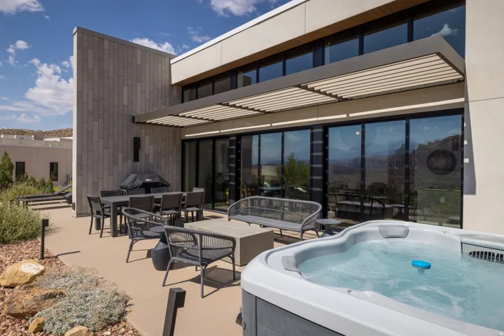 Outdoor patio featuring a built-in hot tub, concrete paving, and a slatted pergola