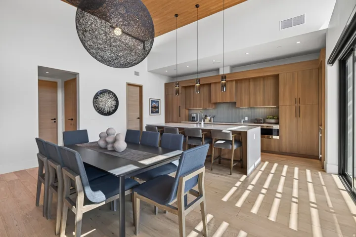 Open-concept living space featuring wood-finish flooring, a kitchen with flat-panel wood cabinetry, and a central island with bar seating