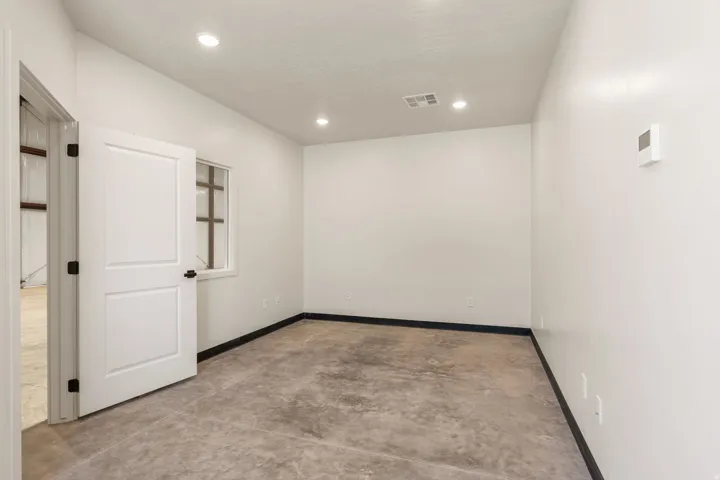 Bright interior space featuring light-toned walls, a concrete floor, and recessed ceiling lighting