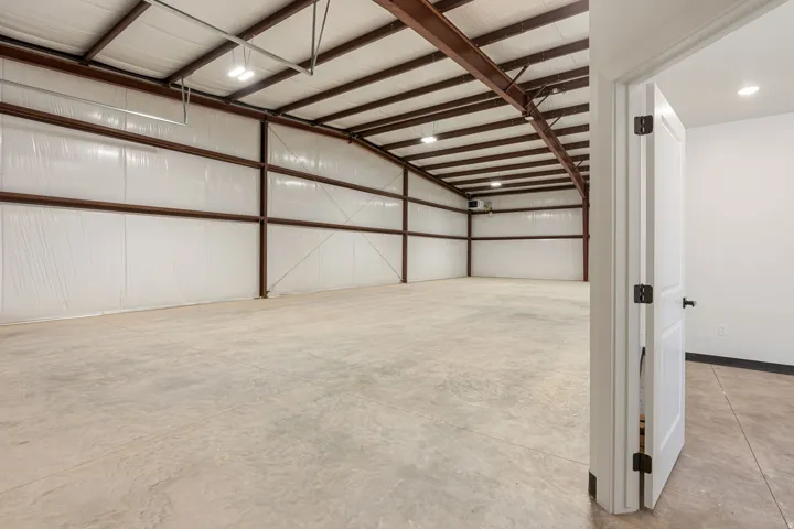 Spacious interior featuring a concrete floor, exposed structural beams, ceiling-mounted lighting, and insulated walls