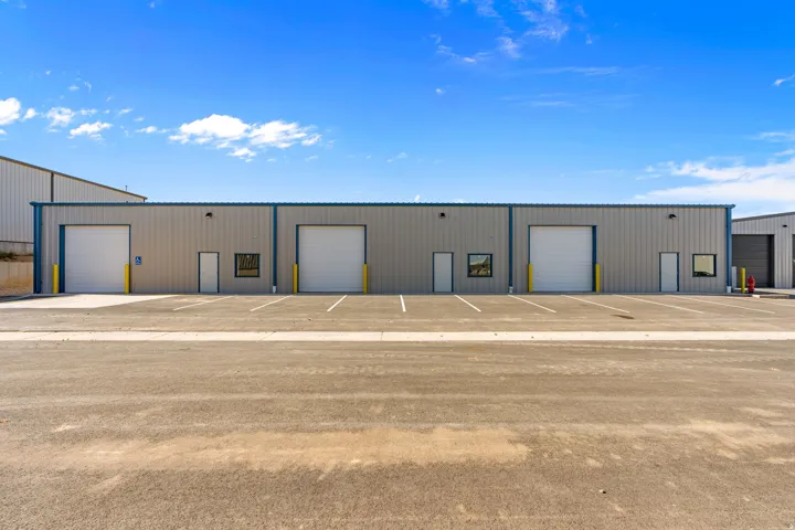 Commercial building featuring multiple roll-up doors, entry doors, and windows