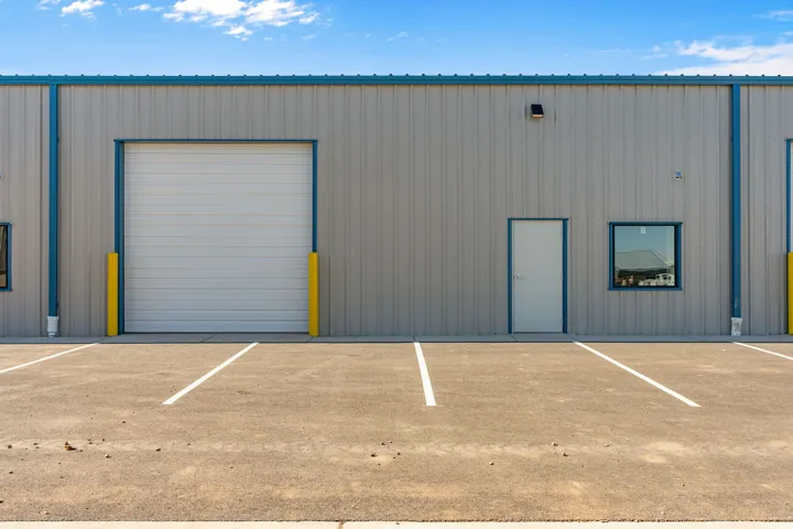 Metal-sided commercial building featuring a roll-up garage door, pedestrian entry, and framed window
