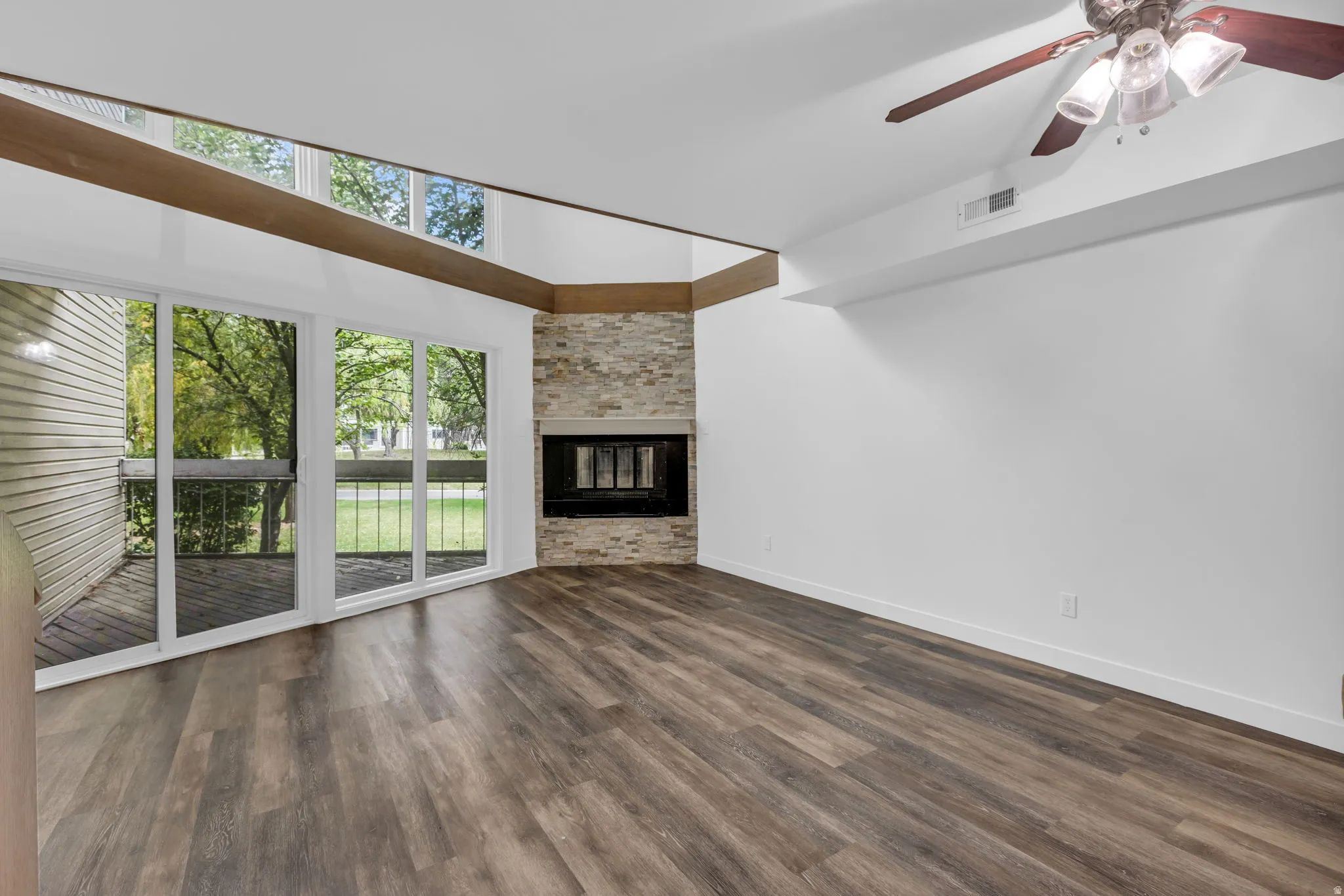 Living space featuring wood-finish flooring and a stone-clad fireplace