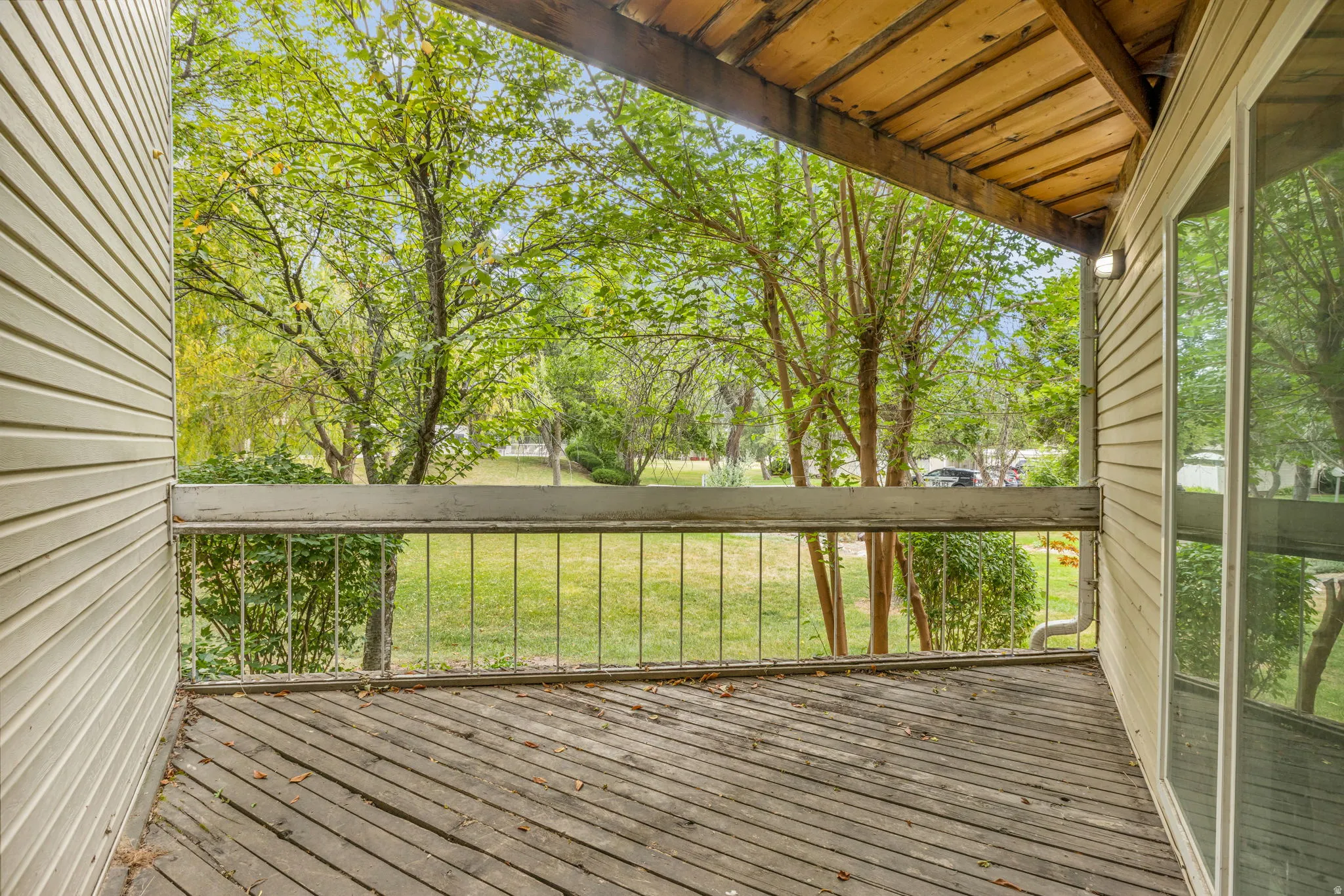 Expansive outdoor deck featuring wood-finish flooring, a metal railing, and a tongue-and-groove wood ceiling