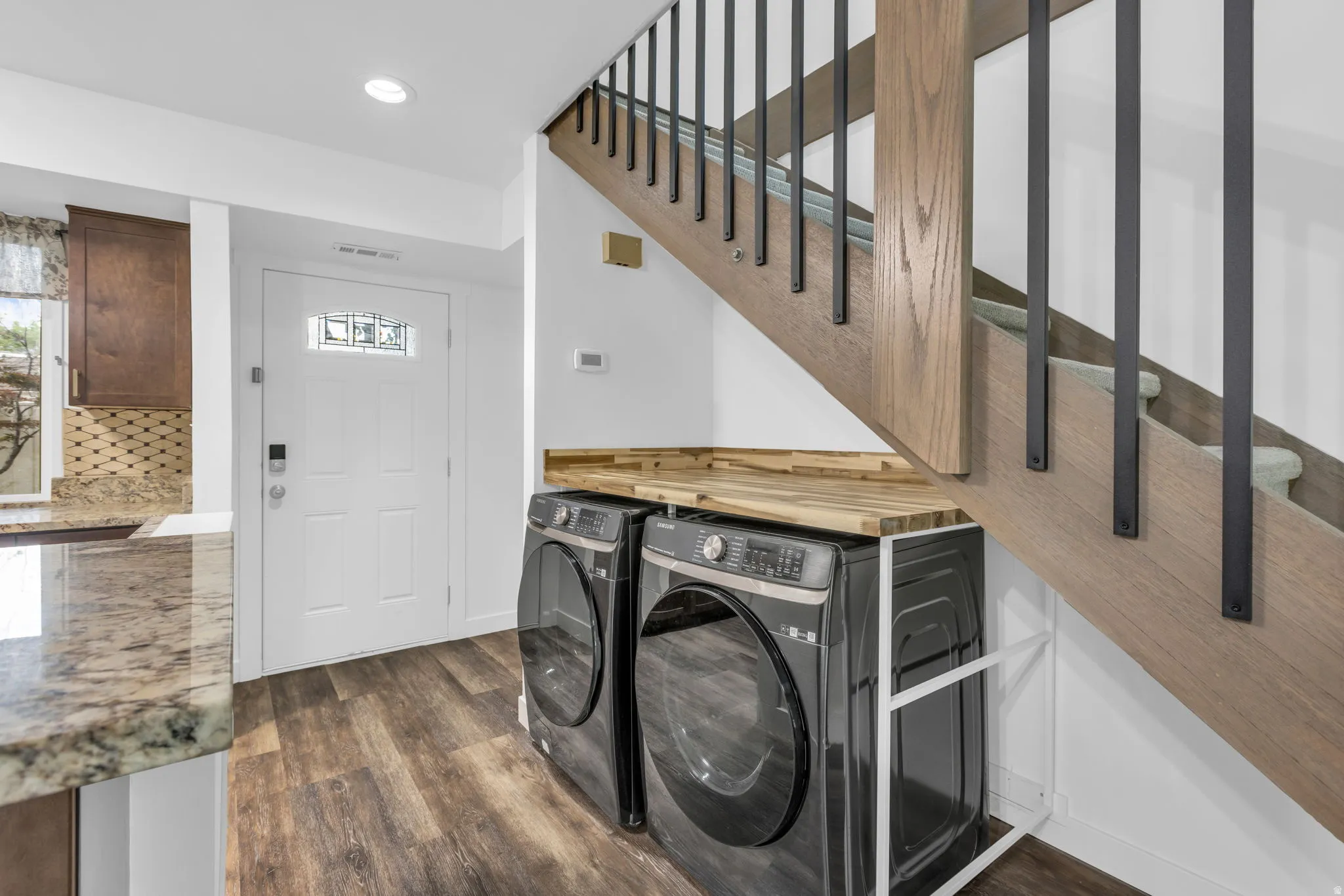 Integrated laundry area featuring stacked appliances with a wood-finish countertop
