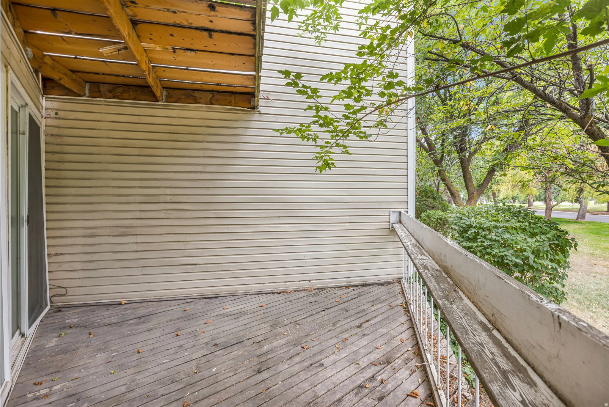 Outdoor deck space featuring wood-finish flooring, a white metal railing, and a sliding glass door entry