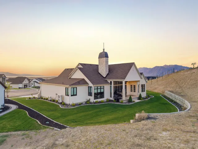Contemporary-style residence featuring a stone chimney with a decorative cap, black-framed windows, and a covered patio